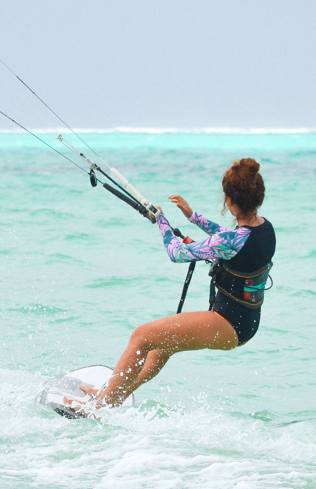 long sleeve surf suit rash guard from lycra with front zipper for women with black base and colourful pink and green sleeves with palm leaves